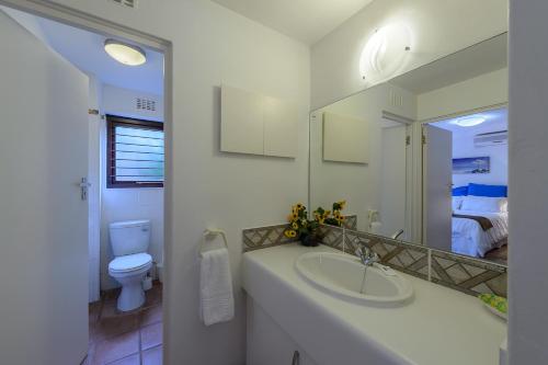 uma casa de banho com um lavatório, um WC e um espelho. em San Lameer Villa 2814 - 3 Bedroom Classic - 6 pax - San Lameer Rental Agency em Southbroom