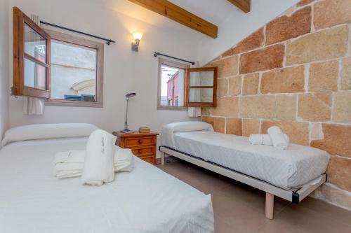 two beds in a room with a stone wall at Ses Andrones 3 in Ciutadella