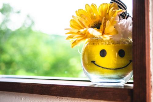 a vase filled with yellow flowers with a smiley face at Guest House Himawari - Vacation STAY 31402 in Mine