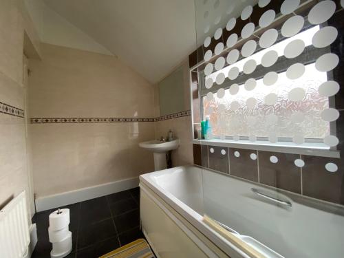 a bathroom with a bath tub and a window at Nice Living Serviced Accommodations 5 in Coventry