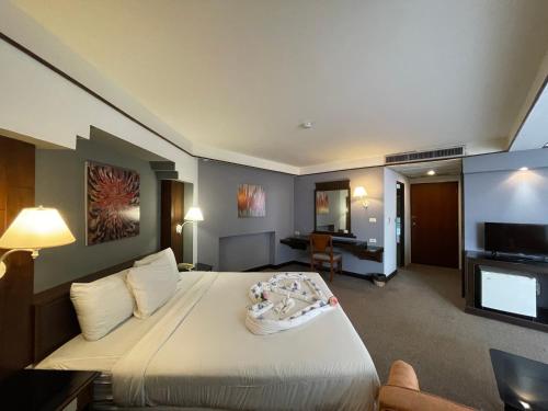 Habitación de hotel con cama y TV en Songphanburi Hotel, en Suphanburi