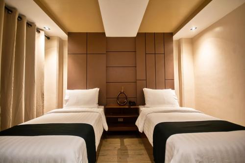 two beds in a hotel room with white sheets at ECL Resort Hotel Boracay in Boracay