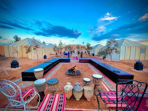 a group of tables and chairs and a fire in a field at Roses desert camp in Merzouga