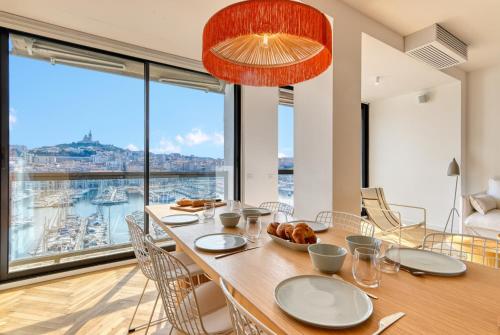 une salle à manger avec une table et une grande fenêtre dans l'établissement La Sentinella - Appt au dessus du Vieux Port, à Marseille