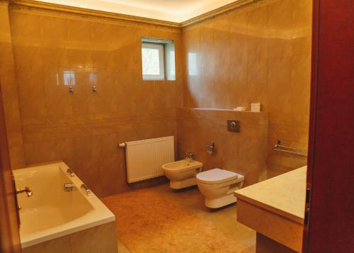 een badkamer met een toilet, een bad en een wastafel bij hotel Memorial in Terezín