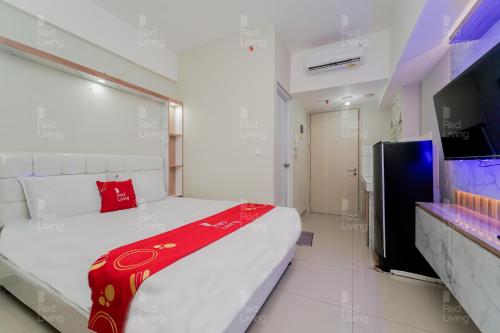 1 dormitorio con 1 cama blanca grande con manta roja en RedLiving Apartemen Springlake Summarecon - Novi Rooms Tower Freesia, en Rawabugel