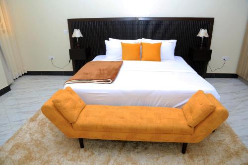 un grande letto con cuscini arancioni e una poltrona arancione di Igwe Home a Kampala