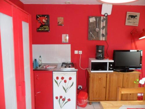 a kitchen with a red wall with a microwave and a stove at Gite Hôtel chambre d' hôtes et roulottes et du Ternois in Saint-Pol-sur-Ternoise