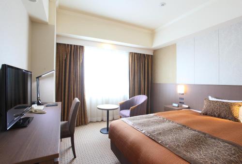 a hotel room with two beds and a television at Hotel Metropolitan Nagano in Nagano