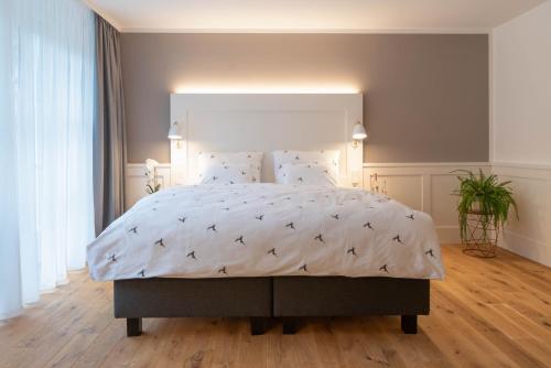 una camera da letto con un grande letto e un piumone bianco di OSCARS Hotel 1415 a Bad Liebenzell