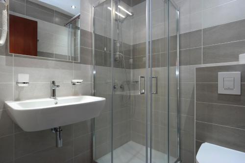 a bathroom with a sink and a glass shower at Hotel Marvel in Arillas