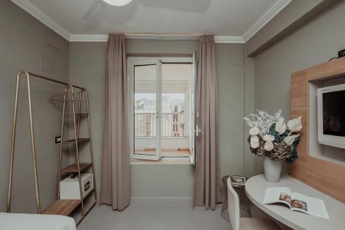 um quarto com uma janela e uma mesa com um vaso de flores em Hotel Marisa em Roma
