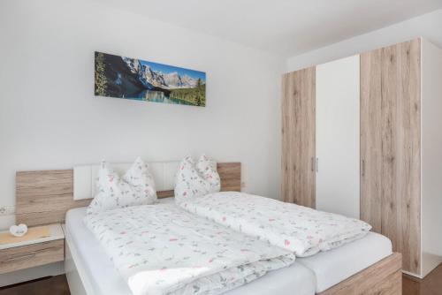 a bedroom with a white bed with a wooden headboard at Trojer Apartment 2 in Sarntal