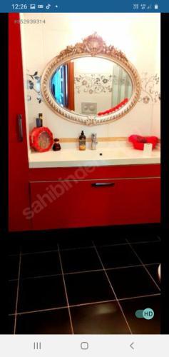 ein Badezimmer mit einem roten Waschbecken und einem Spiegel in der Unterkunft Apartman dairesi in Balçova