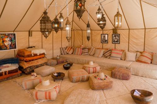 uma sala de estar com sofás e almofadas numa tenda em Beldi camp em Merzouga