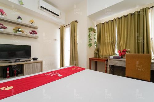 a room with a bed and a tv and curtains at RedLiving Apartemen Margonda Residence 4 - Si Boy in Kemirimuka Tiga