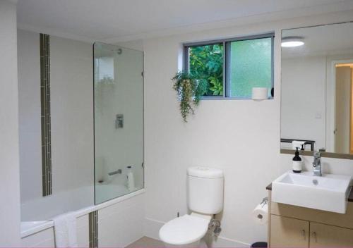 uma casa de banho com um WC, um chuveiro e um lavatório. em Tropical Luxe Apartment em Townsville