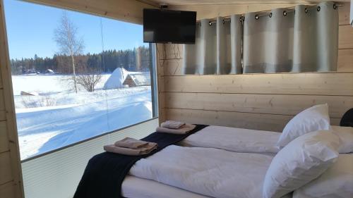 1 dormitorio con 2 camas y ventana grande en Loma Luonnonlapsi Loimu-mökki, en Sotkamo