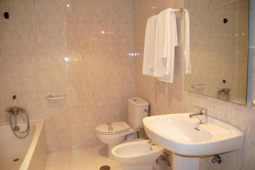 a bathroom with a toilet and a sink and a tub at Hotel Vista Nevada in Darro