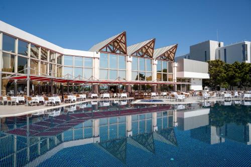 a large building with a pool and tables and chairs at Grand Hotel Ontur Cesme in Cesme