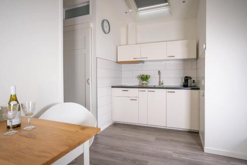 uma cozinha com armários brancos e uma mesa de madeira em Casita del Pueblo em Zandvoort