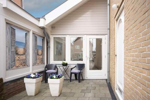 a patio with two white vases with flowers on it at Casita del Pueblo in Zandvoort
