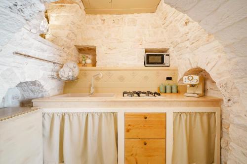 a kitchen with a counter with a sink and a microwave at Trulli di Zia Vittoria in Alberobello