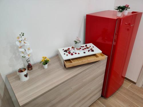 Zimmer mit einem roten Kühlschrank und einem Tisch mit Blumen in der Unterkunft La Prima Dimora Luxury Home in Grumo Appula