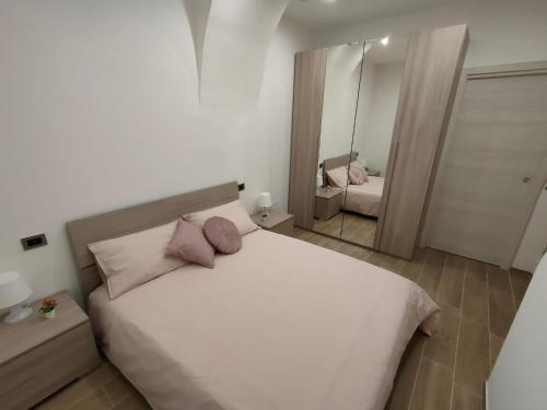La Prima Dimora Luxury Home في Grumo Appula: غرفة نوم مع سرير أبيض مع وسائد وردية ومرآة