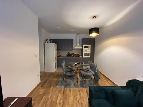 een woonkamer met een tafel en stoelen en een keuken bij Kej Garden - Two bedroom apartment. in Novi Sad