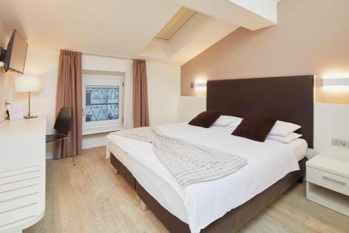 - une chambre avec un grand lit blanc et une fenêtre dans l'établissement Hotel Centrale, à Nago-Torbole
