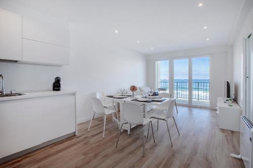 a white kitchen and dining room with a table and chairs at Nahia in Hendaye