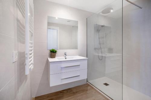 a white bathroom with a sink and a shower at Nahia in Hendaye