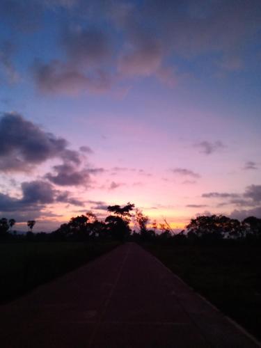 een zonsondergang over een weg in een veld bij หมู่บ้านแสนสุขธานี in Ban Khok Udom (1)