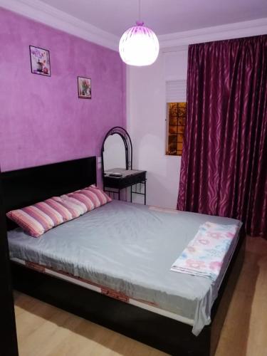 a bedroom with a bed with a purple wall at Mohammed V Airport Appartment in Deroua