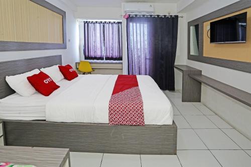 ein Schlafzimmer mit einem Bett mit roten Kissen darauf in der Unterkunft Super OYO 92317 Apartment Riverview By Alima View in Bekasi