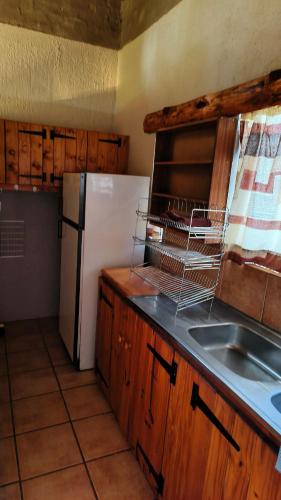a kitchen with a white refrigerator and a sink at Cozy cottage in the Cradle of Humankind in Muldersdrift