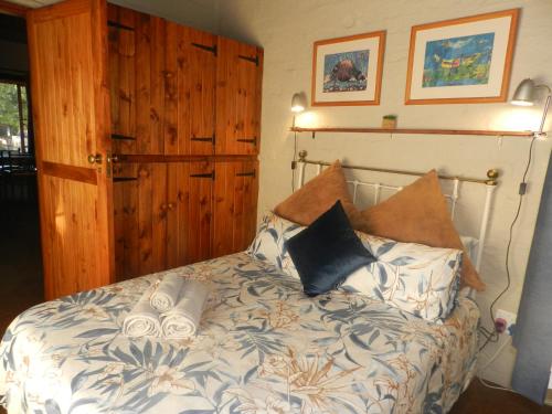 a bedroom with a bed with pillows on it at Cozy cottage in the Cradle of Humankind in Muldersdrift