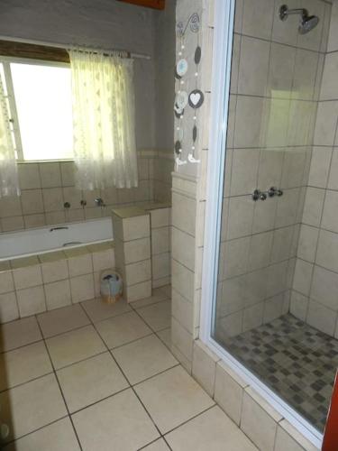 a bathroom with a shower and a tub and a sink at Cozy cottage in the Cradle of Humankind in Muldersdrift