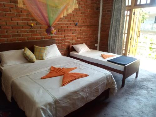 two beds in a room with a brick wall at Nimsara Homestay in Ella