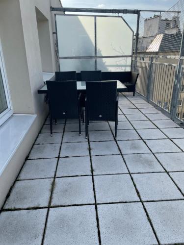 um pátio com uma mesa e cadeiras numa varanda em Nice rooftop hostel em Viena