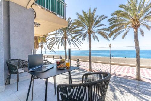 einen Tisch und Stühle mit einem Laptop am Strand in der Unterkunft Expoholidays- Apartaments Paseo Marítimo in Almería