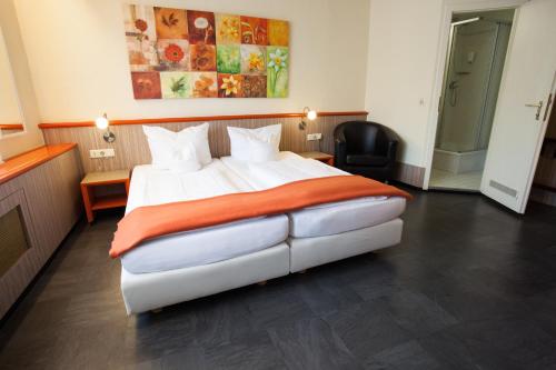 ein Schlafzimmer mit einem großen weißen Bett mit einer orangefarbenen Decke in der Unterkunft Trip Inn Hotel Ariane in Köln