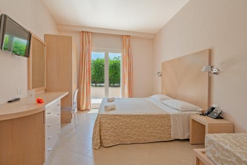 a bedroom with a bed and a kitchen with a television at Hotel Villaggio Cala Di Volpe in Capo Vaticano