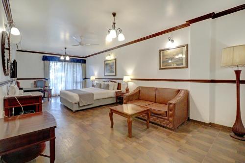 a hotel room with a bed and a couch and a table at Citrus Chambers Mahabaleshwar in Mahabaleshwar