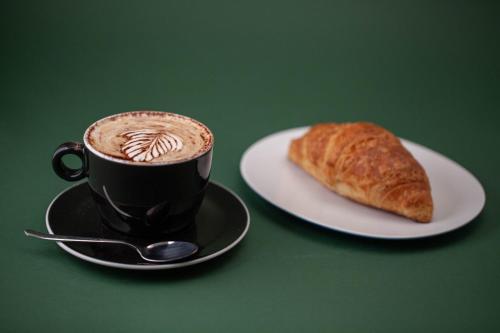 a cup of coffee and a plate with a croissant at BF Glam-Apartments in Perugia