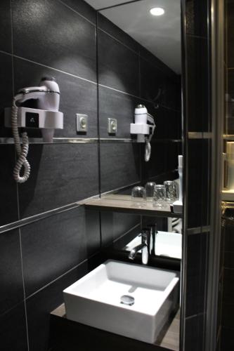 ein Badezimmer mit einem weißen Waschbecken und einem Telefon in der Unterkunft Hôtel Crocus Caen Mémorial in Caen