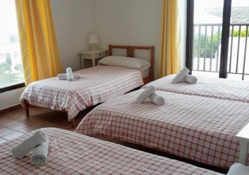 Habitación con 3 camas con sábanas rojas y blancas. en CASIOPEA, en Ciutadella