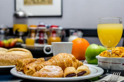 a table with a plate of pastries and a glass of orange juice at Virgen de los Reyes in Seville