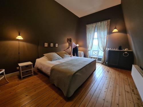 a woman standing on a bed in a bedroom at B&B 't Kasteel & 't Koetshuys in Veurne